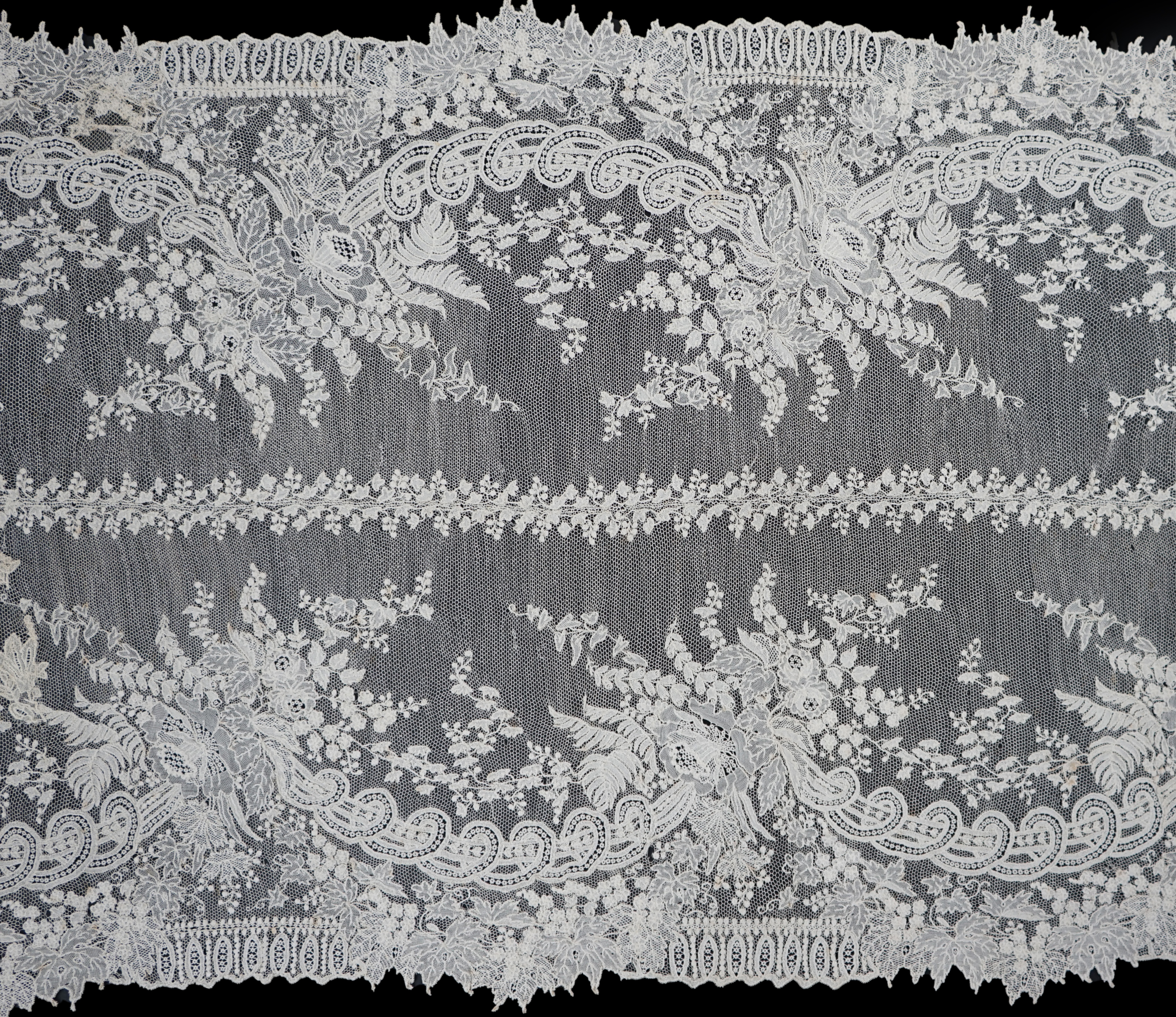 A 19th century Brussels Point de gaze needle lace stole 228cm long x 37cm wide, made from two lengths of the same patterned lace, invisibly joined along the centre of the stole, the raw end edges carefully finished with